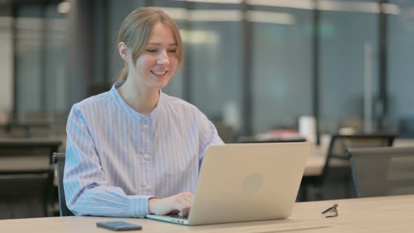 Young Woman Talking on Video Call on Laptop in Office