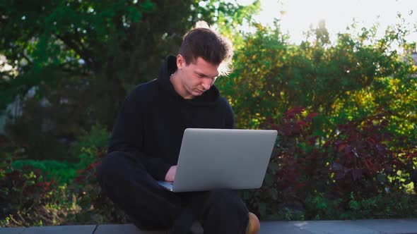 Guy Works at Laptop in City Park