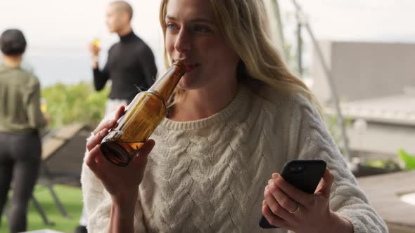 Young Caucasian woman drinking a beer on a rooftop