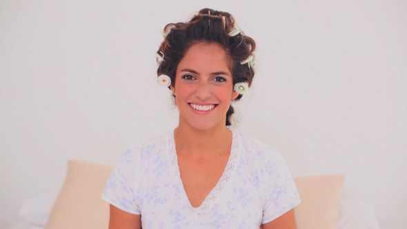 Happy Woman In Hair Curlers Applying Gloss