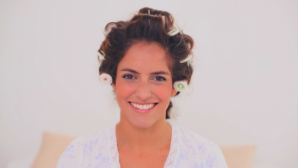 Pleased Woman In Hair Curlers Applying Gloss