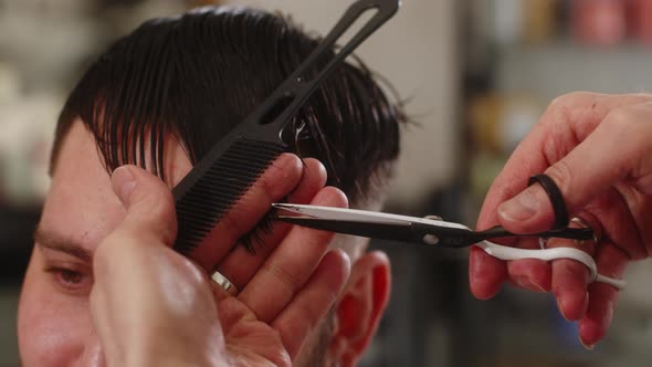 Closeup Man's Hands Cut the Hair on the Head of a Young Guy in the Salon