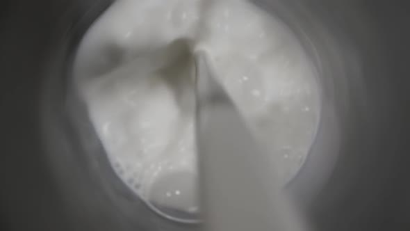 Top View of Milk Being Poured From Transparent Bottle in a Glass on Black Wooden Table