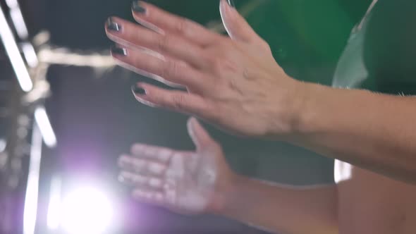 Female Strong Arms of a Weightlifter Clap Their Hands Smeared with Magnesia Preparing to Perform an