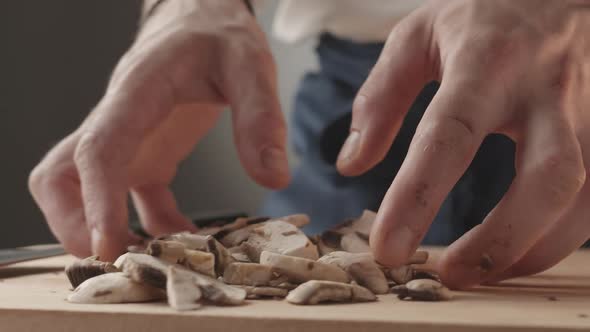 The Young Chef in Restaurant Uniform Works in the Kitchen and Holds Mushrooms