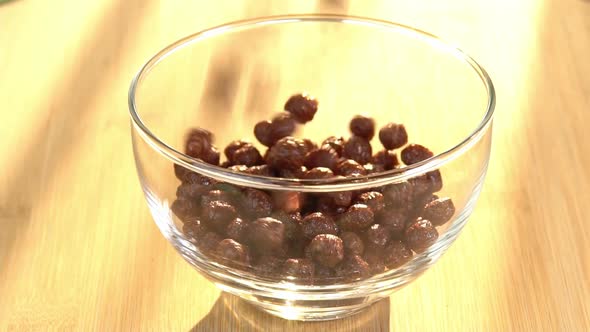 Chocolate cereals falling in a bowl. A healthy breakfast poured in glass along sunrise