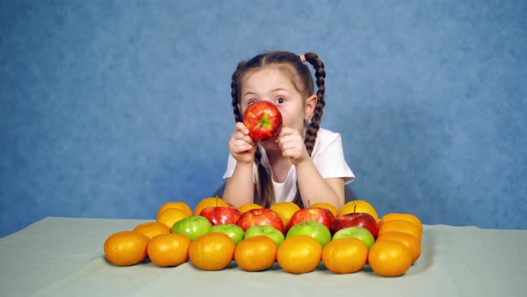 Little girl sits at table. Happy child girl and lot of fruit