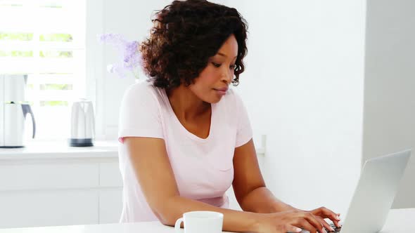 Woman using laptop in kitchen 4k