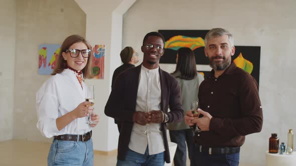 Guests Posing for Camera with Champagne at Party in Art Gallery