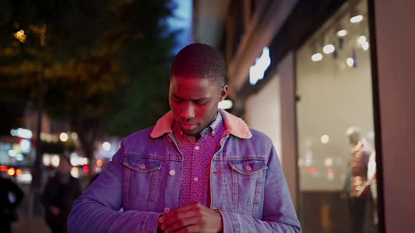 Black man in denim jacket looking on watch