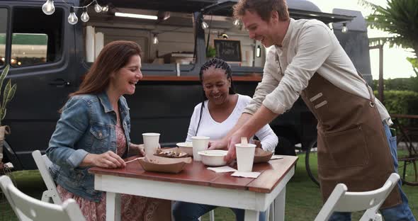 Multiracial people eating food truck meal outdoor