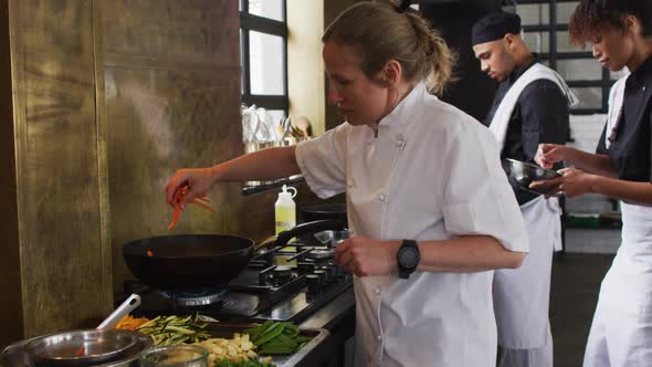 Caucasian female chef teaching diverse group preparing dishes and smiling