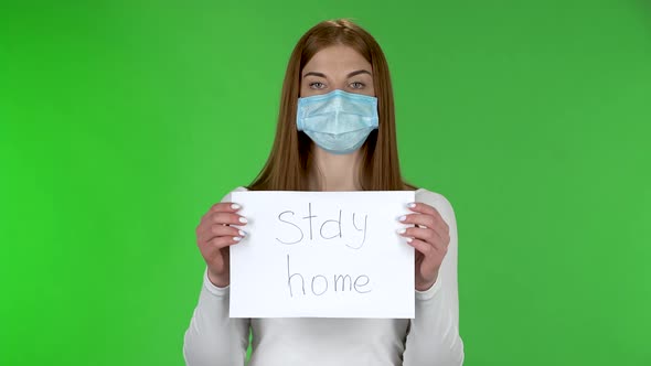 Portrait of Young Girl in Medical Protective Face Mask Looking at Camera and Holding a Poster with