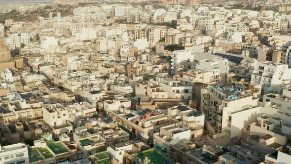 Beige Brown Apartment Blocks in Hot Area in Sunlight on Malta Island, Aerial Drone Forward Tilt Down