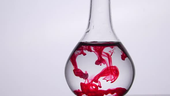 Taking laboratory blood analysis. Red drop falls into water liquid, medical test. Glass flask