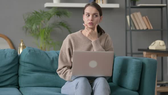 Woman with Laptop Reacting to Loss on Sofa