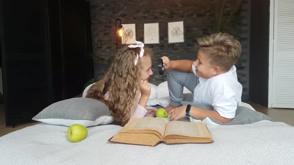 The boy looks at the girl through a magnifying glass.