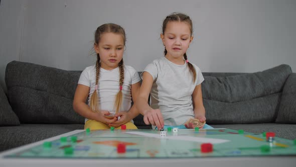 Two Little Girls Playing Table Board Game Rolls Dice and Moves Game Figure