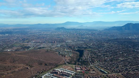 Aerial orbit of Las Condes, Santiago, Chile. Skyline and island hills in the background on a cloudy