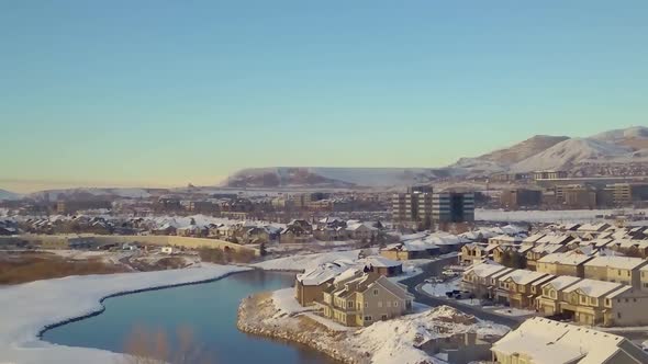 Aerial dolly zoom above a river and pond with suburbs, office buildings and mountains in the backgro