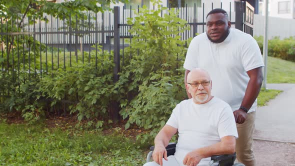 African-American caregiver and old disabled man in a wheelchair. Nurse and patient.