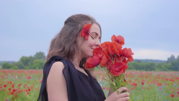 Portrait of Pretty Young Woman Holding and Sniffing Bouquet of Flowers in Hands Looking in the