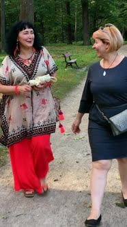 Two Mature Adult Women Walking in Park Talking and Smiling