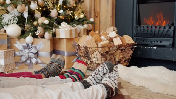 Close-up of Feet Moving While People Relaxing on Floor in Cozy House with Fireplace and Christmas