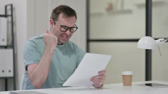 Successful Young Man Celebrating Documents