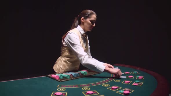 Casino Croupier Girl Distributes Cards on the Poker Table Top. Black Background. Slow Motion