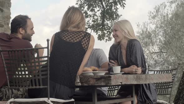 Group of Four Happy Friends Has Italian Breakfast in Natural Rural Scenic Outdoor During Summer