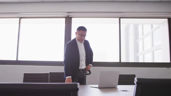 Senior businessman using laptop while standing in modern office in slow motion