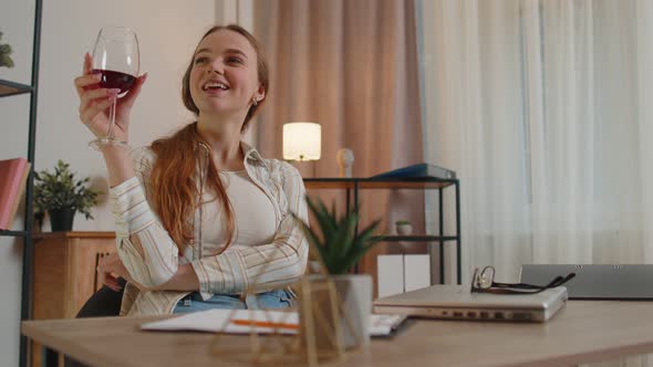 Woman Freelancer Drinking Wine After Online Distance Remote Conversation on Laptop at Home Office