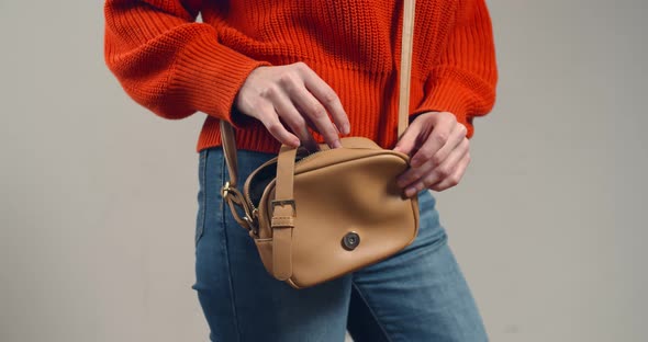 Closeup of Young Woman Putting Condom in Handbag Isolated on Grey Background