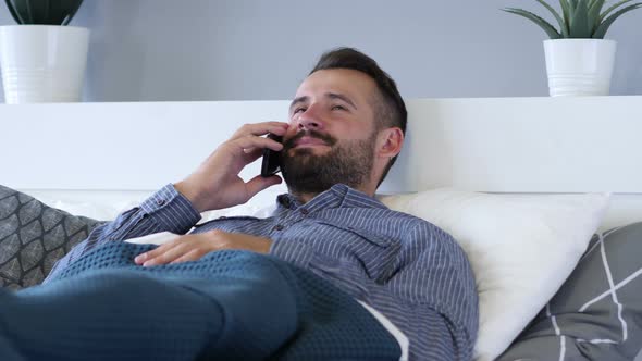 Man Talking on Phone while lying in Bed