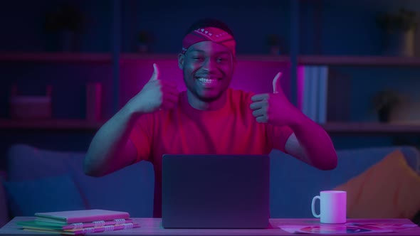 Happy Black Guy Sitting At Laptop Gesturing ThumbsUp At Home