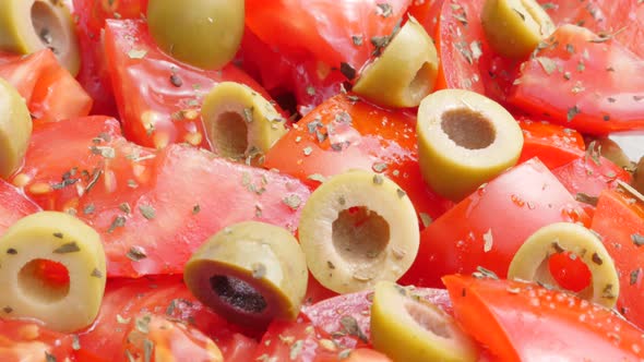 Juicy olives and tomatoes mixed in healthy salad  with oil and spices close-up 4K 2160p 30fps UltraH