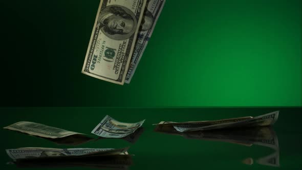 American $100 Bills Falling onto a Reflective Surface