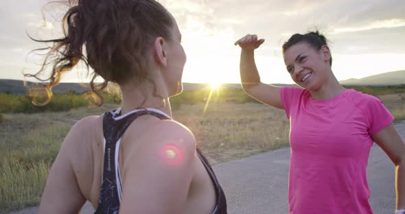 Two Multiethnic Girls Stretching Together in the Street Stretching Their Legs Before a Run