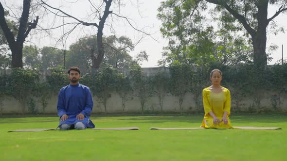 Thunderbolt Yoga pose or Diamond Yoga pose or Vajrasana is being done by an Indian couple