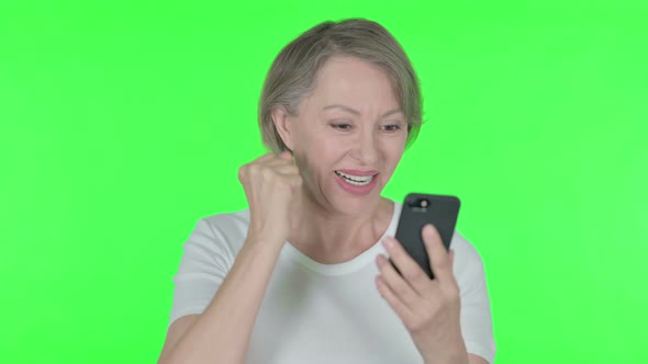 Old Woman Celebrating on Smartphone on Green Background