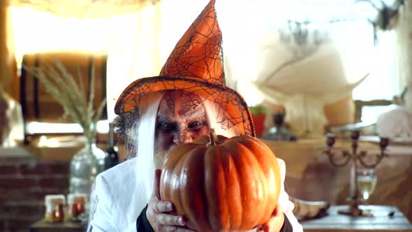 Old Man Ready for Halloween Party. Evil Wizard Hold Orange Pumpkin. Mature Man Magician in Witch Hat