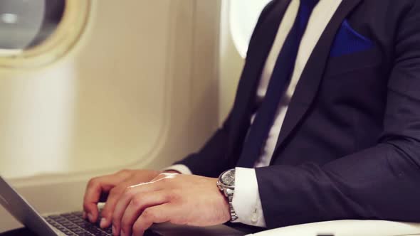 Young Businessman Using Laptop Computer in Airplane