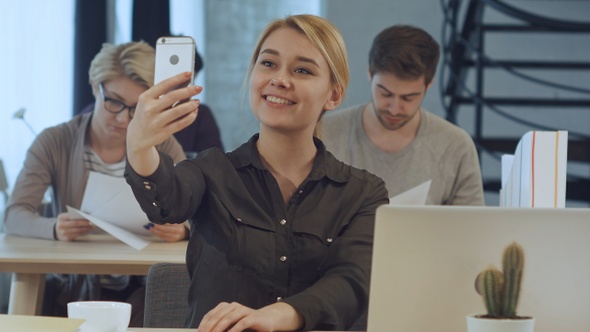 Young businesswoman making selfie at her workplace