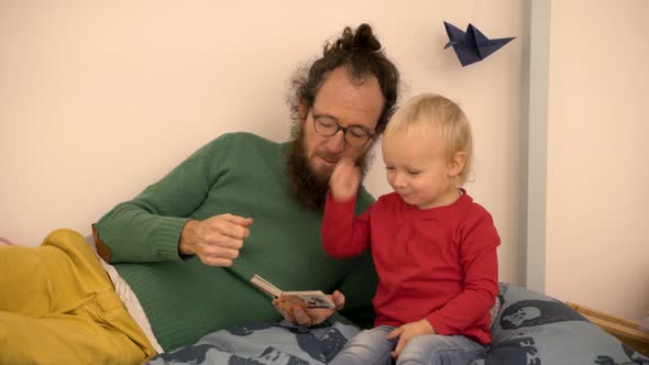 Father reading book to Infant son at children room.