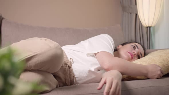 Exhausted or Bored Young Sleepy Woman Falls Down on Sofa
