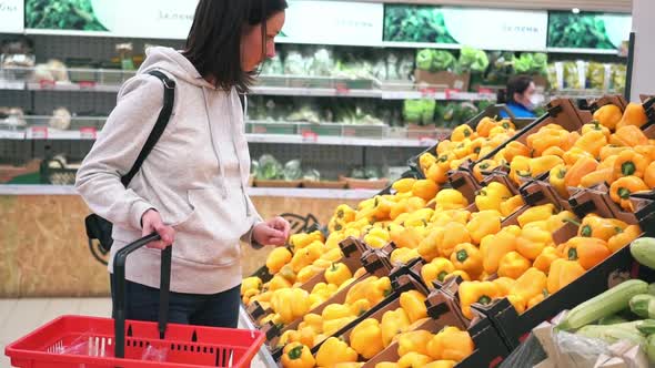 A Woman's Hand Takes Yellow Vegetables in a Supermarket