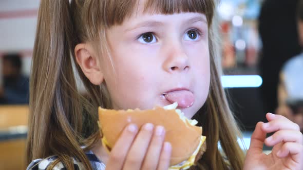 Pretty child girl eating fast food at restaurant.