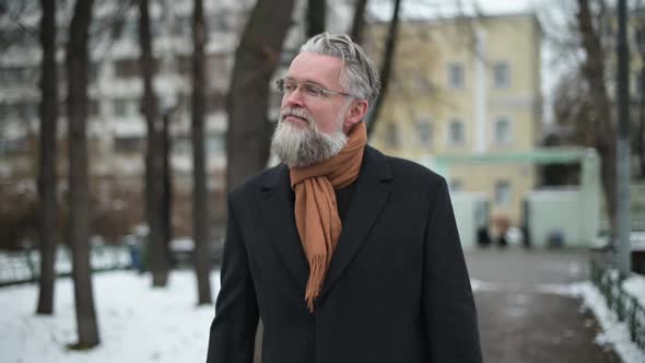 Medium shot of a respectable man with glasses walking in the park