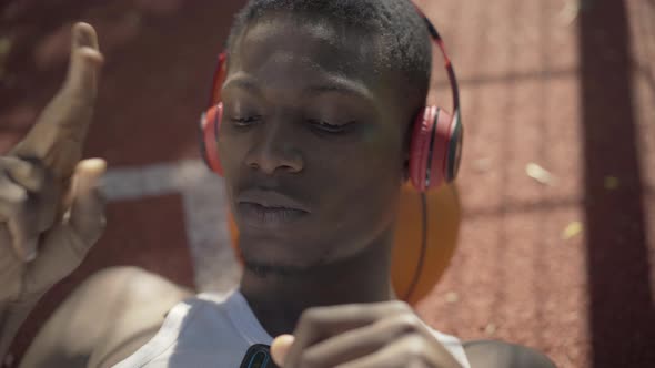 Close-up Face of Young African American Man Lying on Basketball Ball and Singing. Portrait of alt